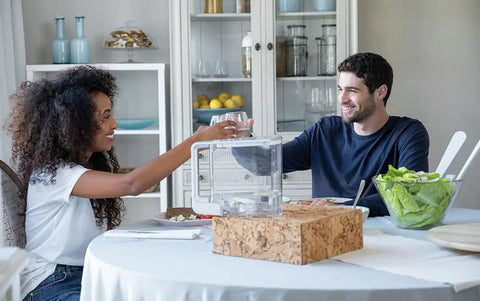 Two people at a table with Extra Clean Water Tank For Countertop Reverse Osmosis System - BPA Free, Shatterproof, Pitcher Style Tank.