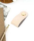 Slick Double Pack PU Leather Cord Organizer Ties For Reusable USB Charger Straps and Earphone Holders, beige cord organizer on desk.