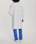 Back view of Relaxed Fit Unisex Full-Length Lab Coat With Snap Front And Two Spacious Pockets, worn by person in blue pants.