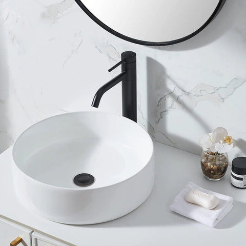 Go-To Matte Black Vessel Sink Faucet Tall And Sleek For 1 Hole Mount 360 Degree Swivel Single Handle Mixer Spout Stainless Steel Bathroom Faucet With Pop Up Drain next to white ceramic sink on marble countertop.