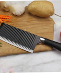 Front view of LIFKOME stainless steel crinkle slicer with black handle on cutting board.
