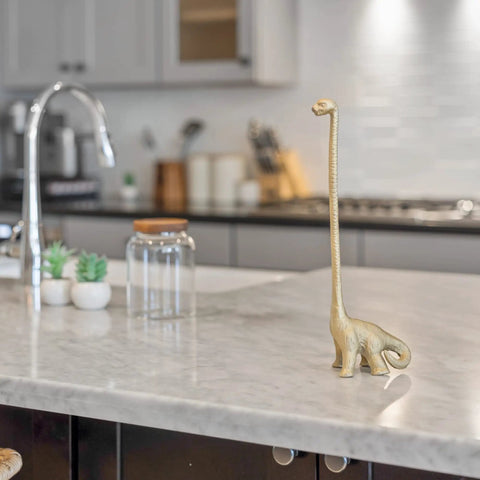 Totally Gold Dino Paper Towel Holder Stand for Kitchen and Bathroom Decor on marble countertop, dinosaur-shaped, gold finish