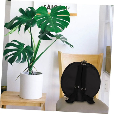 Tour Ready Waterproof Drum Backpack And Oxford Cloth Gig Bag With Padded Adjustable Straps placed on a chair next to a potted plant.