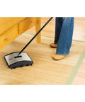 Lightweight Manual Carpet And Hard Floor Sweeper Featuring Dual Rotating Brush Roll Plus Corner Edge Brushes, operating under furniture.