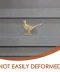 Top Shelf Brass Pheasant Drawer Knob With Rich Golden Finish on gray cabinet door, showcasing intricate bird design, tarnish proof.