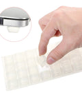 Hand holding a clear rubber bumper from a 32 pack of Thirty Two Piece Clear Rubber Bumpers Super Sticky Self Adhesive Pad.