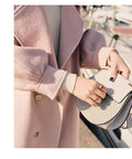 Woman wearing a pink coat holding a gray handbag with chain. Elegant fashion style, modern accessories.