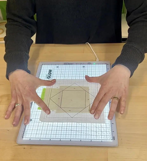 Hands using Portable LED Light Pad For Crafting And Quilting 10 By 13 Inch, Ultra Bright Four Level Illumination for tracing.