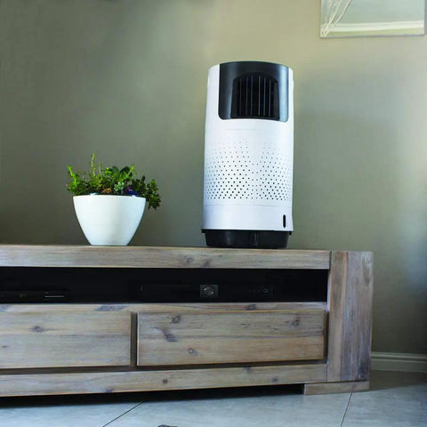Portable Evaporative Air Cooler For Bedroom And Office Electric Standing Cooling Fan That Completely Beats The Summer Heat And Keeps You Chillin All Day Long Compact Personal Room Cooler In White on a wooden table next to a small plant.