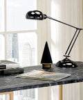 Adjustable Standing Computer Desk With Built Storage And Power Port, Sleek Faux Marble Work Table For Home Office, Gold Metal Frame next to lamp and books.