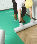 A worker laying out the Top Notch Temporary Floor Protection Roll For Construction And Home Reno Green Non Adhesive Surface Shield Film.