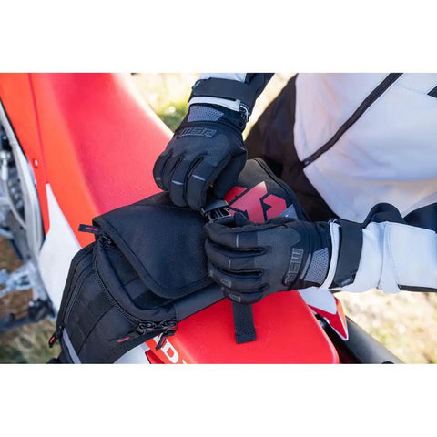 Person securing Compact Must Have Trail Saver Tool Kit with Fanny Pack on motorcycle, wearing gloves.