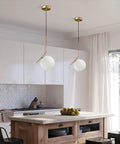 Mid Century Modern 1 Light Globe Pendant Chandelier In Brushed Gold With White Glass Ball For Kitchen Island Industrial Retro Style Single Pendant Light Fixture displayed in a modern kitchen setting.