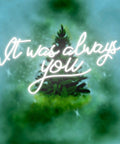 Neon sign with phrase 'It was always you' glowing over a blurred green background.