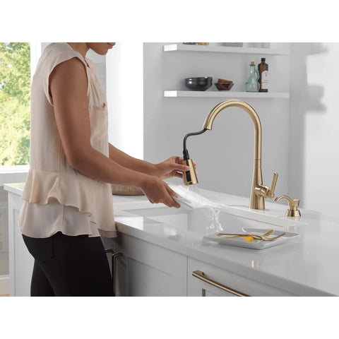 Modern Single Handle Kitchen Sink Faucet With Pull Down Spray Head And Built In Soap Dispenser, Magnetic Self Docking, Brushed Gold Finish, Single Hole Mount in use while washing a dish.