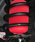Rear air suspension spring bag, red rubber with black coil, installed on vehicle.