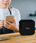P-Touch CUBE Plus Bluetooth Label Maker PT-P710BT Portable Label Printer on table with person using smartphone