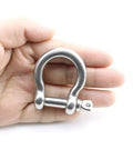 Hand holding a 304 stainless steel bow shackle, part of the 4 Pack Ultra Tough 304 Stainless Steel Bow Shackle With Screw Pin Anchor Hardware Built Like A Tank For Paracord Bracelets Rigging Outdoor Survival And Heavy Duty Camping.