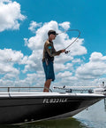 Person fishing on a boat using Laguna LT Spinning Reel 3 Plus 1 Ball Bearings 5.3 to 1 Gear Ratio under a cloudy sky.