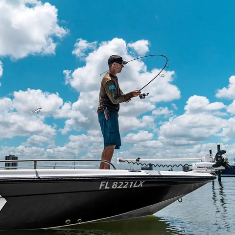 Person fishing on a boat using Laguna LT Spinning Reel 3 Plus 1 Ball Bearings 5.3 to 1 Gear Ratio under a cloudy sky.