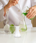 Scientist using 12 Pack Plastic Flask Set For Science Class, Wide Mouth Erlenmeyer Style Bottles with liquid and leaf