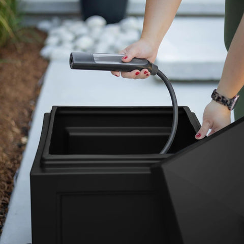 Woman placing hose in Built Tough Black Garden Hose Bin Storage Box That Holds Up To 100 Feet Of Standard Hose 17 By 17 By 18 Inches UV Fade Resistant Weatherproof Outdoor Organizer