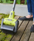 Cordless 18 Volt Patio Surface Cleaner With Telescoping Handle being used to scrub moss off wood deck.