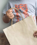 Child holding Bulk 500 Pack Heavy Duty Kraft Paper Bags 10x13 Inches With Handles 10x5x13 Inches Brown Gift Shopping Retail Bags