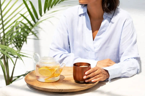 Renewed 6 Oz Smart Heated Coffee Mug With App Precision Temp Control next to a glass teapot with lemon slices.
