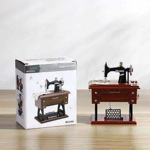 Handcrafted Vintage Sewing Machine Music Box With Wind Up Mechanism beside its packaging on a wooden surface.