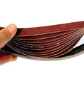Get This Awesome 10 Pack Sanding Belts Set For Your Belt Sander Machine With 533 By 9mm Size Including All Grits From 40 To 1000 For Smoothing Wood Metal Or Plastic Like A Pro Today: close-up of sanding belts in hand.