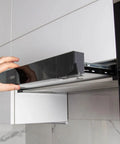 Hand adjusting black kitchen range hood panel with stainless steel filters installed