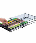 Hand reaching into K Cup Holder Drawer With Crystal Tempered Glass Top, Heavy Duty Metal Coffee Pod Organizer, holding 42 K Cups.
