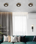 Three 4.5 Inch Solid Brass LED Recessed Downlights on ceiling in a modern living room, part of a Six Pack Top Shelf Led Can Lights.