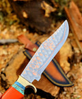 Dope Copper Damascus Fixed Blade Knife With Resin Handle showing hammered blade close-up next to leather sheath on wood