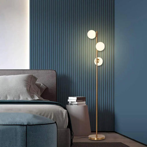 Three Globe Brushed Brass Floor Lamp, Modern LED Standing Light For Living Room, Bedroom, And Office next to bed