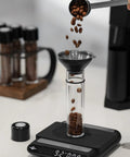 Single Dose Coffee Storage Tubes With One Way Exhaust Valve 8 Piece Set Espresso Dosing Jars and Walnut Holder filled with coffee beans.
