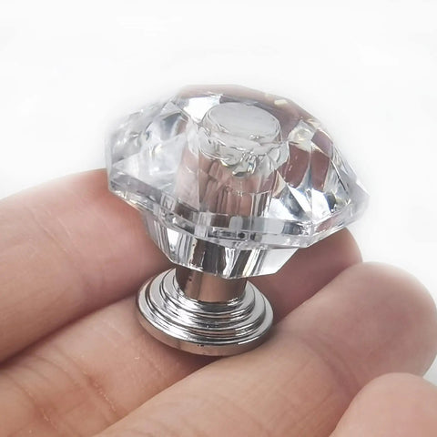 Close-up of Clear Crystal Drawer Knobs 26 Pack 24mm Diamond Shaped Acrylic Cabinet Pulls held in hand with metal base.