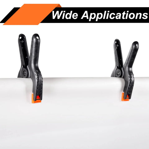 Two black 3.5-inch plastic spring clamps with orange tips clamped to a white pipe