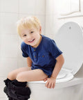 Child sitting on elongated toilet seat with built-in toddler seat and soft close for easy potty training family friendly white design.