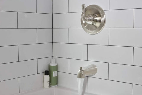 Elmhurst Shower Trim Kit With Tub Spout In Brushed Nickel Finish, installed over white subway tiles, water flowing from spout