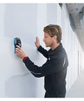 Man using Hands Down Best Pro Grade Wall Scanner to detect live wires and studs on a wall in a construction setting.
