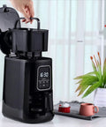 Compact Automatic Freshly Ground Coffee Brewer With Onboard Bean Grinder And Programmed Cup Settings, black unit with grinder visible.