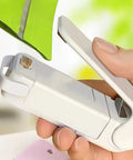 Slick Mini Portable Handheld Bag Sealer For Fresh Snack Storage And Grocery Plastic Packaging Clamps Hassle Free Heat Seal Tool Compact Kitchen Gadget White in use, closing a green packaging.