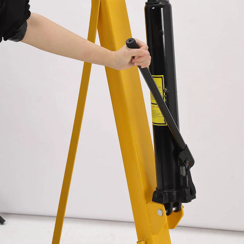 User operating the hydraulic mechanism of the 4000 LB Folding Engine Crane Beefy Steel Hoist Cherry Picker for auto repairs.