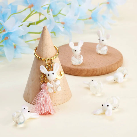 Rabbit Lampwork Glass Beads 10 Pcs Cute Bunny Spacer Beads on display with tassel keychain and blue flowers in background