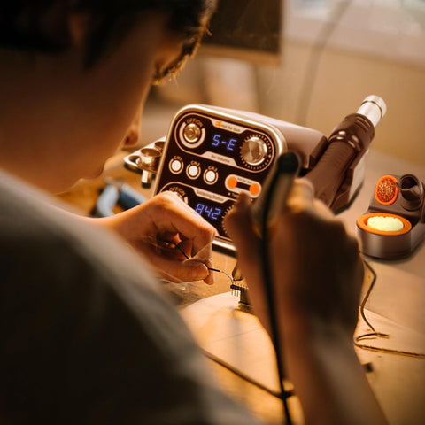 Person using 2 In 1 Hot Air Rework Station Kit With 760W Soldering Iron And Soldering Mat for PCB repair, dual LED display visible