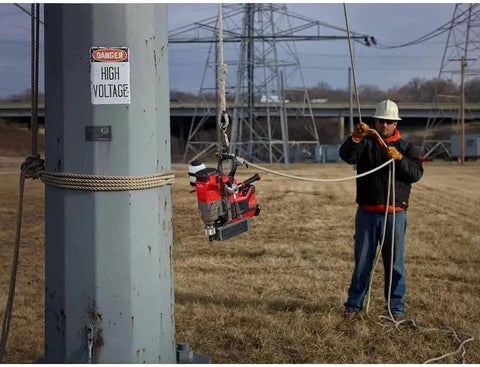 Worker using No Sweat Cordless Magnetic Drill Kit For Professional Linemen Featuring A Heavy Duty Brushless Motor And One Point Five Inch Capacity on a utility pole.