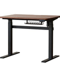 Top Shelf Electric Standing Desk With Ultra Wide Worktop Effortless Height Adjustment Hidden Wire Basket Natural Walnut Finish in a side view.