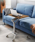 Mobile standing laptop desk with wood surface, adjustable height, and wheels on a blue sofa, ideal for sitting or standing anywhere.